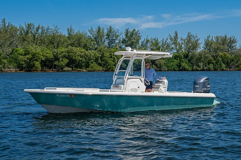 Slide: The Image of 2012 Everglades 243 Center Console boat cruising on a serene lake with lush greenery. - 25