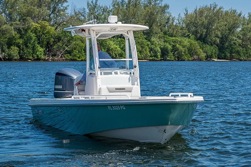 Slide: The Image of 2012 Everglades 243 Center Console boat on water, with Yamaha engine, near lush shoreline. - 29