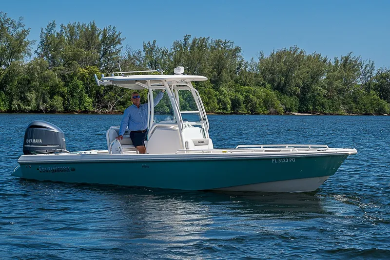 Slide: The Image of 2012 Everglades 243 Center Console boat on water, with Yamaha engine, near lush shoreline. - 31