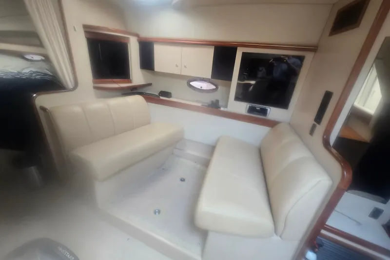 Slide: The Image of Interior of 2001 Cruisers Yachts 3470 Express with beige seating and wood accents. - 10
