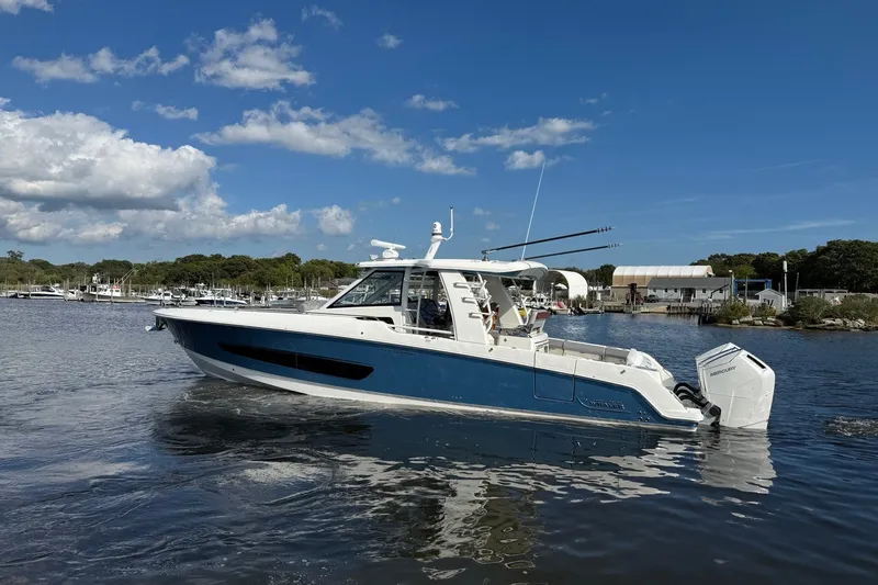 Slide: The Image of 2024 Boston Whaler 420 Outrage boat on calm water under a clear blue sky. - 2