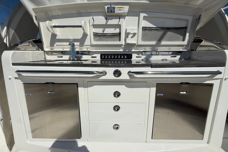 Slide: The Image of 2024 Boston Whaler 420 Outrage boat kitchen with stainless steel appliances and storage. - 24