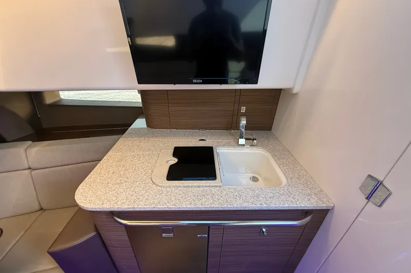 Slide: The Image of 2024 Boston Whaler 420 Outrage interior with modern kitchenette and TV setup. - 40