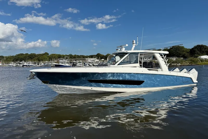 Slide: The Image of 2024 Boston Whaler 420 Outrage boat on calm water under a clear blue sky. - 1