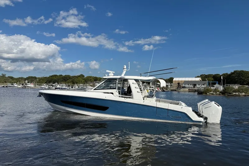 Slide: The Image of 2024 Boston Whaler 420 Outrage boat on calm water under a clear blue sky. - 5