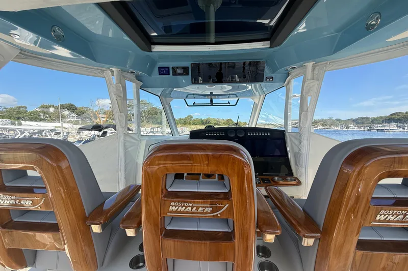 Slide: The Image of Interior view of 2024 Boston Whaler 420 Outrage boat cockpit with wooden seats. - 27