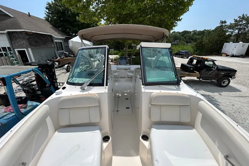 Slide: The Image of 2012 Pursuit DC 265 Dual Console boat with open cockpit and seating, parked outdoors. - 23