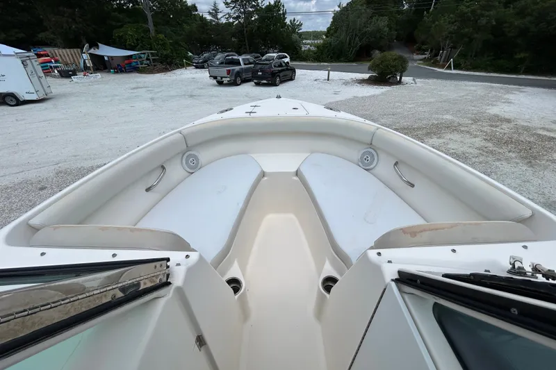 Slide: The Image of 2012 Pursuit DC 265 Dual Console boat interior with seating, parked on gravel lot. - 21