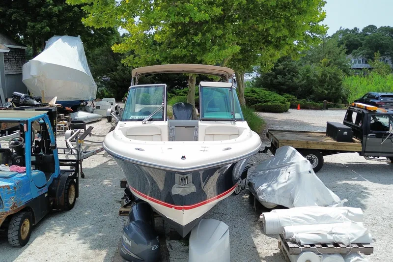 Slide: The Image of 2012 Pursuit DC 265 Dual Console boat in a yard, surrounded by equipment and trees. - 4