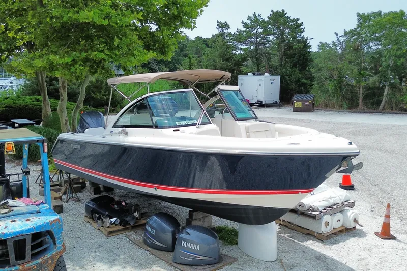 Slide: The Image of 2012 Pursuit DC 265 Dual Console boat on dry dock, surrounded by trees and equipment. - 3