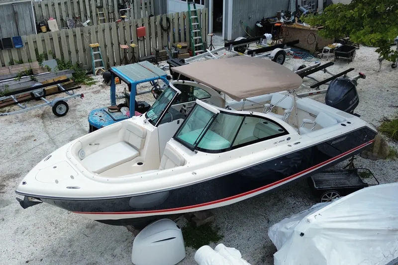 Slide: The Image of 2012 Pursuit DC 265 Dual Console boat in a yard, with a beige canopy. - 1