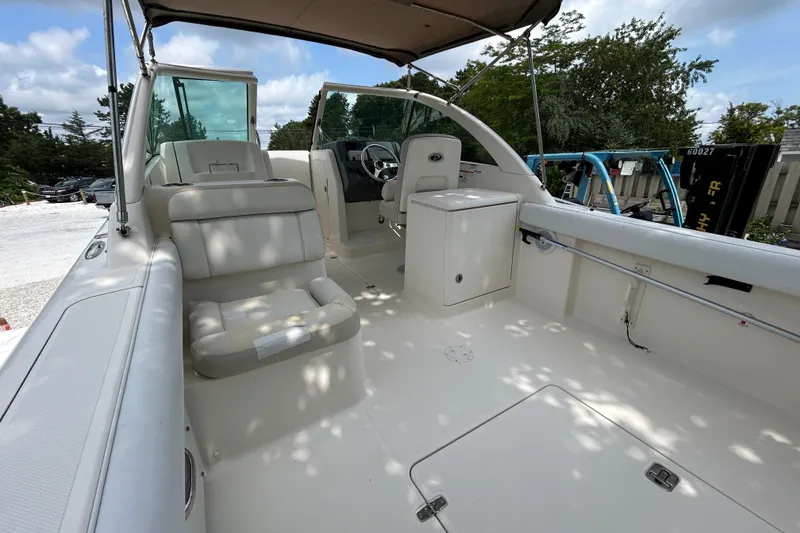 Slide: The Image of 2012 Pursuit DC 265 Dual Console boat interior with seating and storage under a canopy. - 11