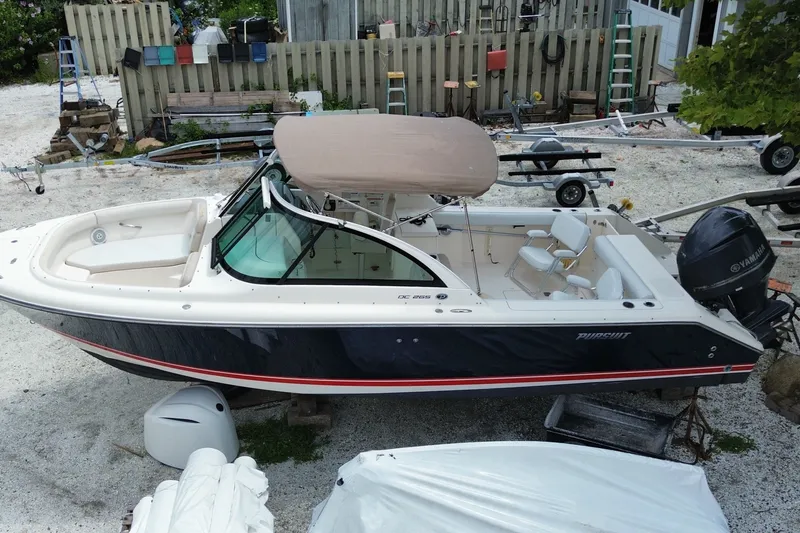 Slide: The Image of 2012 Pursuit DC 265 Dual Console boat with Yamaha engine, parked on gravel. - 2