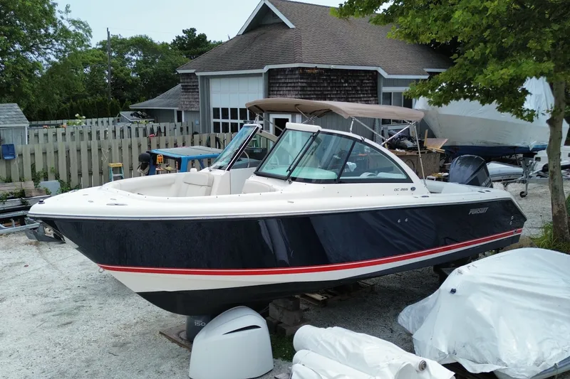 The Image of 2012 Pursuit DC 265 Dual Console boat parked near a house, showcasing sleek design. - 0