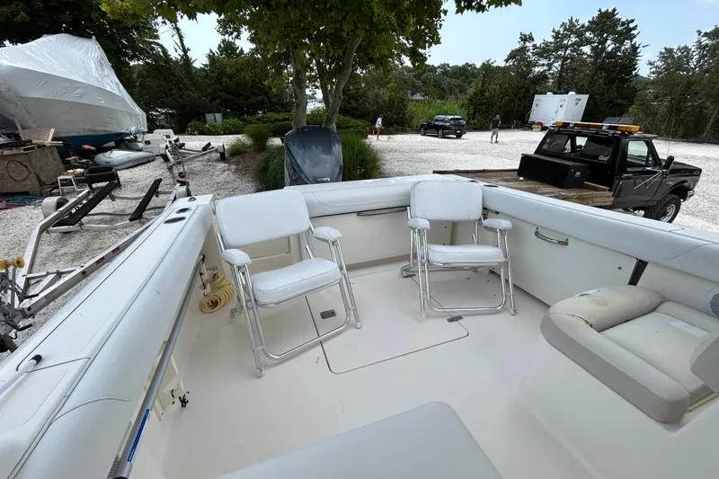 Slide: The Image of 2012 Pursuit DC 265 Dual Console boat interior with white seating and outdoor setting. - 8