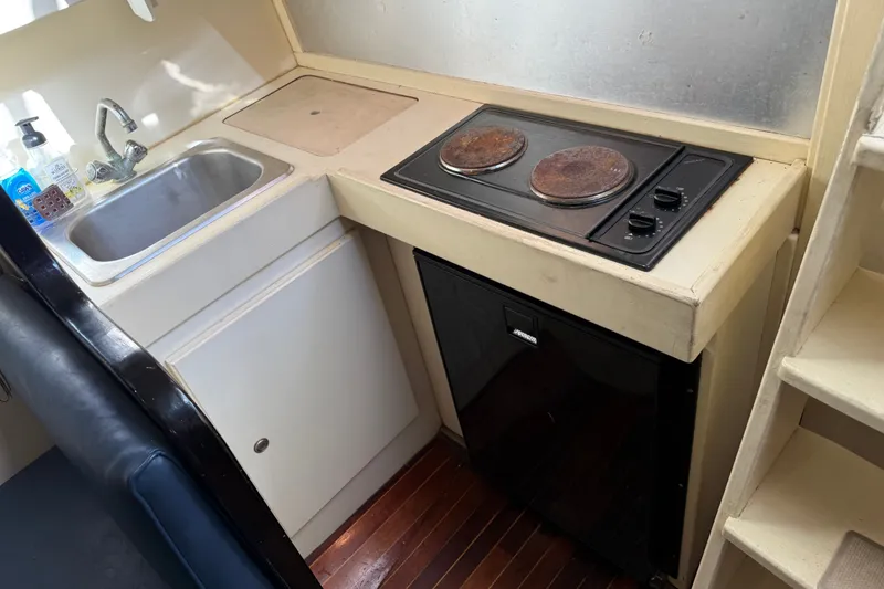 Slide: The Image of Compact kitchen area in a 1998 Dorado 36 Express boat with sink, stove, and mini fridge. - 43