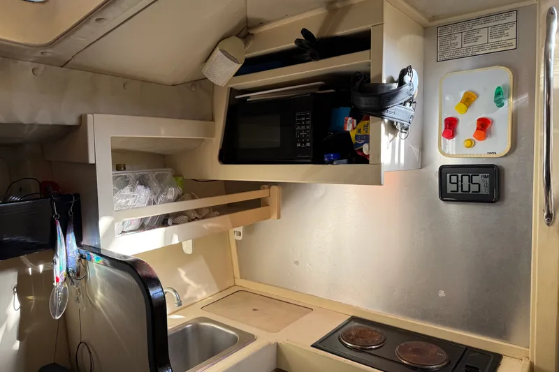 Slide: The Image of 1998 Dorado 36 Express boat kitchen with microwave, sink, stove, and wall clock. - 34