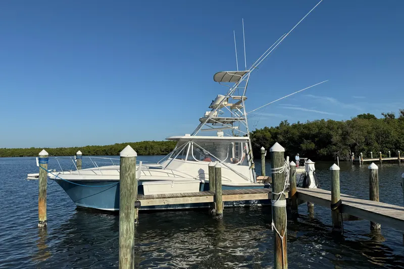 Slide: The Image of 1998 Dorado 36 Express boat docked at a marina under clear blue skies. - 58