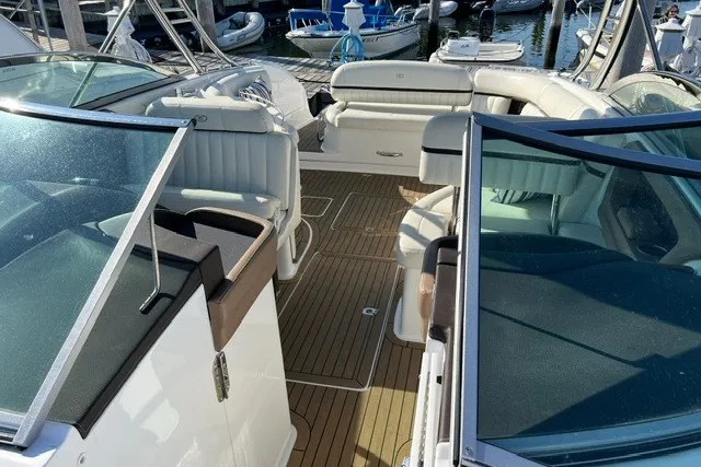 Slide: The Image of 2016 Cobalt 336 boat interior with white seating and wooden deck at a marina. - 4