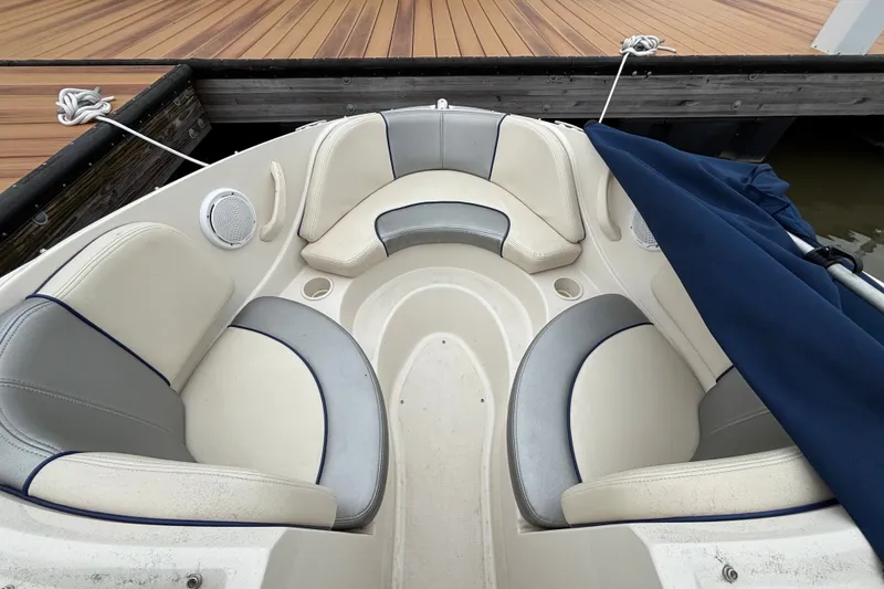 Slide: The Image of 2010 Sea Ray 185 Sport boat interior with beige and gray seating at dock. - 3