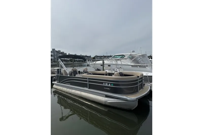The Image of 2025 Harris Cruiser 230 pontoon boat docked in a marina, featuring sleek design and spacious seating. - 1