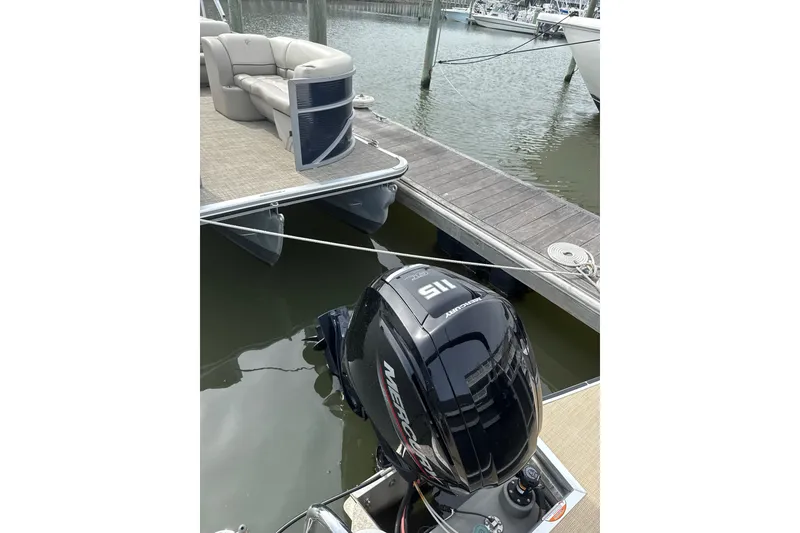 Slide: The Image of 2025 Harris Cruiser 230 pontoon boat docked with Mercury outboard motor. - 11