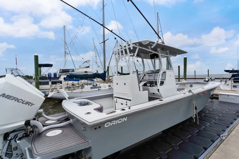 Slide: The Image of 2025 Orion 29 boat docked, featuring Mercury engine, surrounded by sailboats under a blue sky. - 1