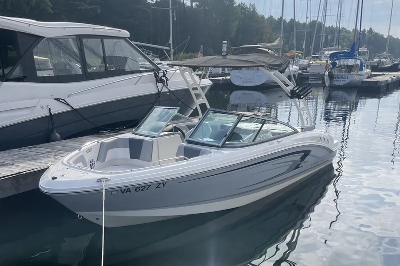 The Image of 2021 Chaparral 21 SSi boat docked at a marina with surrounding yachts. - 0