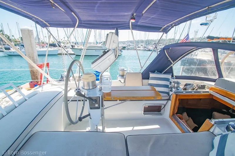Slide: The Image of 1988 Hylas 44 Center Cockpit sailboat interior with helm, seating, and marina view. - 44