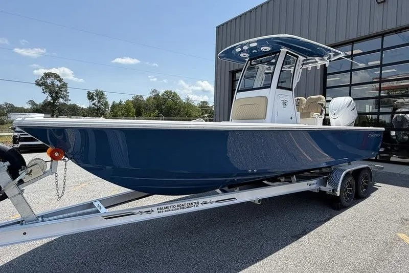 The Image of 2027 Sportsman Masters 247 Bay Boat in blue on trailer, parked outside a building. - 1