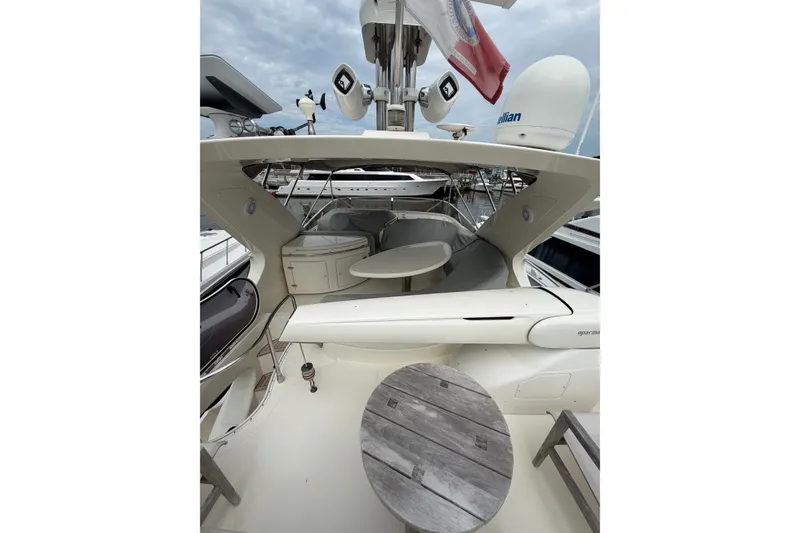 Slide: The Image of 2006 Azimut 55E yacht deck with seating and table, docked under cloudy skies. - 42
