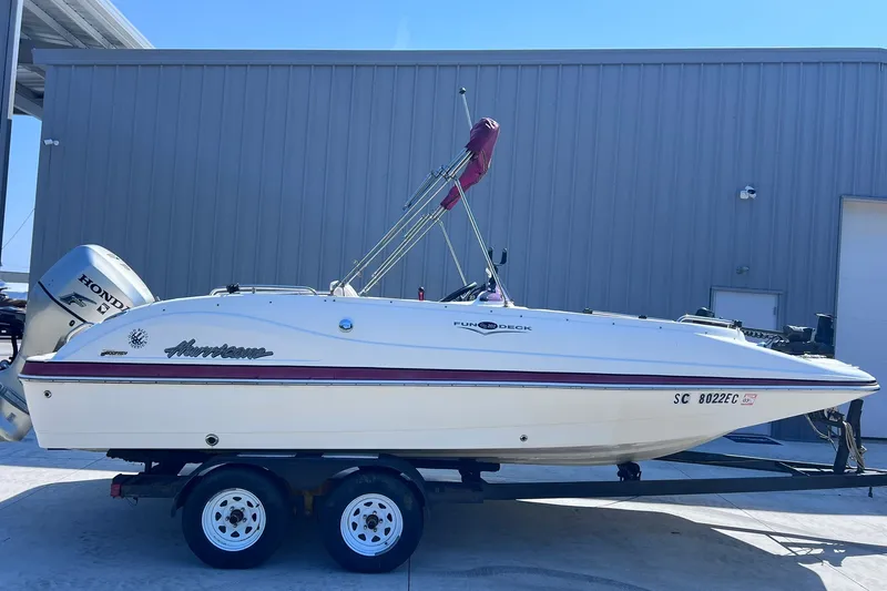 The Image of 2005 Hurricane FunDeck GS 202 OB boat on trailer, parked outside a building. - 1