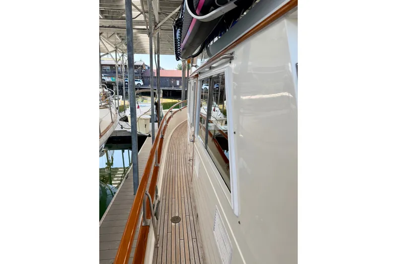 Slide: The Image of 1988 Grand Banks 42 Classic yacht docked, showcasing teak deck and cabin windows. - 29