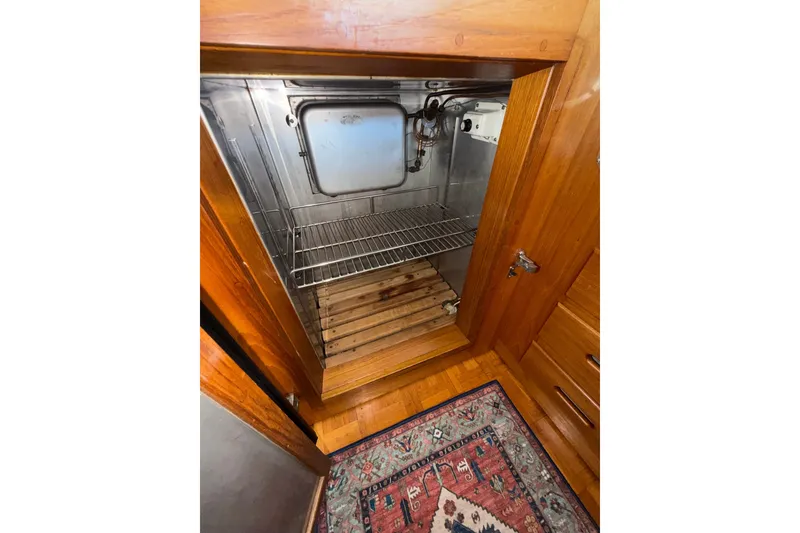 Slide: The Image of Wooden cabinet with open door revealing metal interior and wire rack, Grand Banks 42 Classic 1988. - 42