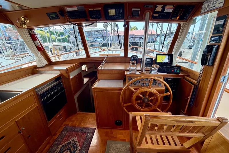 Slide: The Image of 1988 Grand Banks 42 Classic yacht helm with wooden wheel, navigation instruments, and cozy interior. - 37