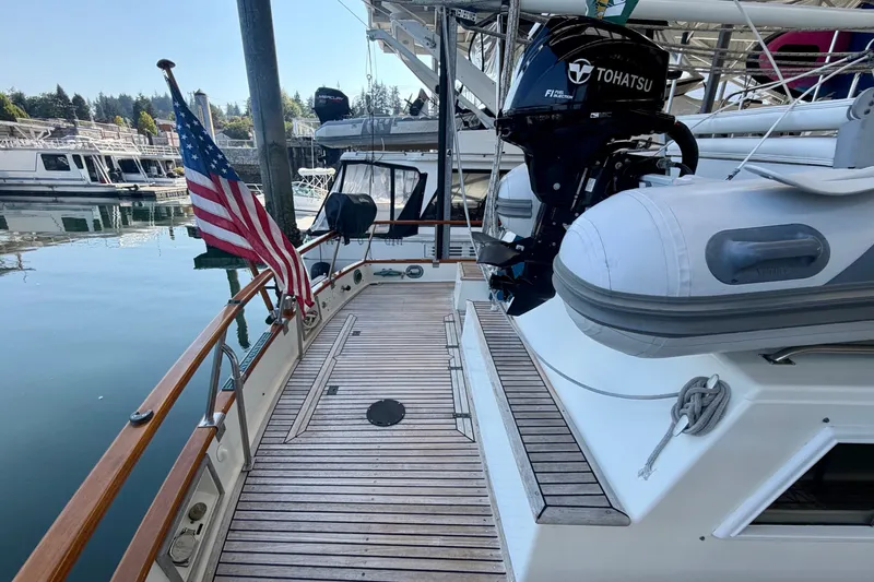 Slide: The Image of 1988 Grand Banks 42 Classic yacht with American flag, docked with inflatable boat and outboard motor. - 19