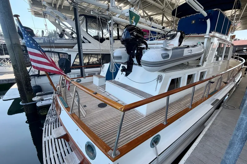 Slide: The Image of 1988 Grand Banks 42 Classic yacht docked, featuring wooden deck and American flag. - 18