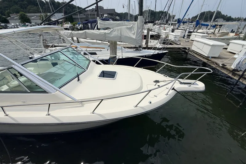 Slide: The Image of 1999 Pursuit 2860 Denali boat docked at a marina, surrounded by other vessels. - 3
