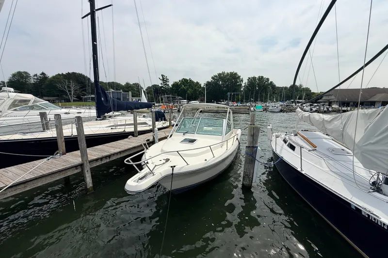 Slide: The Image of 1999 Pursuit 2860 Denali boat docked at a marina, surrounded by other vessels. - 2