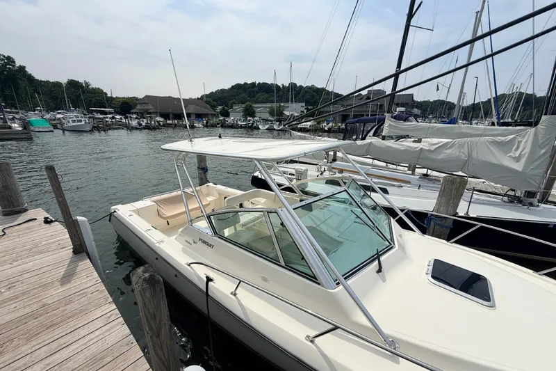Slide: The Image of 1999 Pursuit 2860 Denali boat docked at a marina with surrounding sailboats. - 4