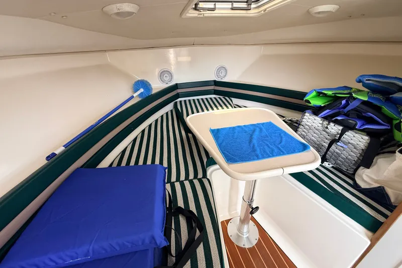 Slide: The Image of 1999 Pursuit 2860 Denali cabin interior with striped seating, table, and life jackets. - 15