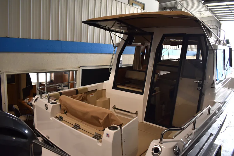 Slide: The Image of 2019 Ranger Tugs R-23 boat interior, featuring spacious seating and modern design in a garage setting. - 13