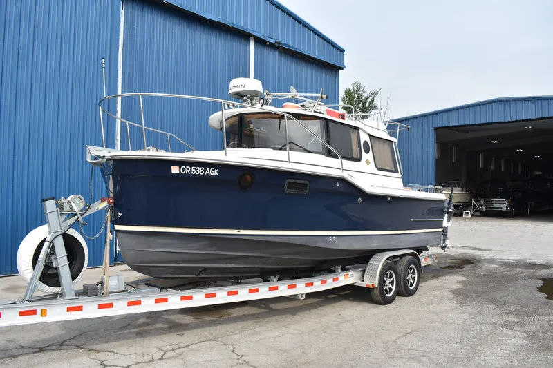 Slide: The Image of 2019 Ranger Tugs R-23 boat on trailer near blue warehouse. - 6