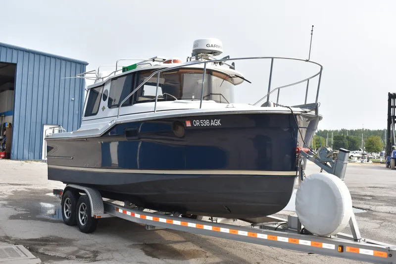 Slide: The Image of 2019 Ranger Tugs R-23 boat on trailer, parked near a blue building. - 4