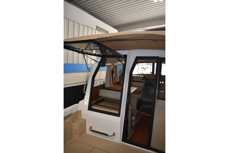 Slide: The Image of 2019 Ranger Tugs R-23 boat interior with open cabin door, showcasing seating and helm. - 15