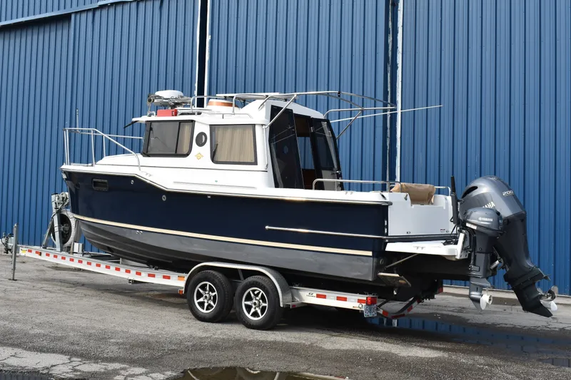 Slide: The Image of 2019 Ranger Tugs R-23 boat on trailer, parked by blue warehouse. - 7