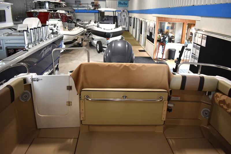 Slide: The Image of 2019 Ranger Tugs R-23 boat interior in showroom with various boats displayed. - 16