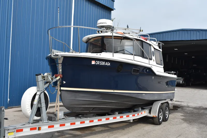 Slide: The Image of 2019 Ranger Tugs R-23 boat on trailer, parked outside a blue warehouse. - 5