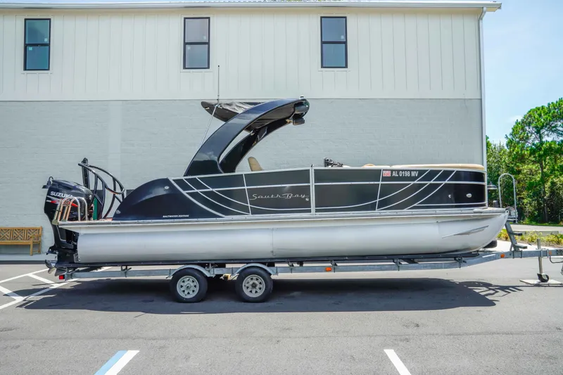 Slide: The Image of 2016 South Bay 724 SPORT DLX pontoon boat on trailer, parked outdoors. - 2