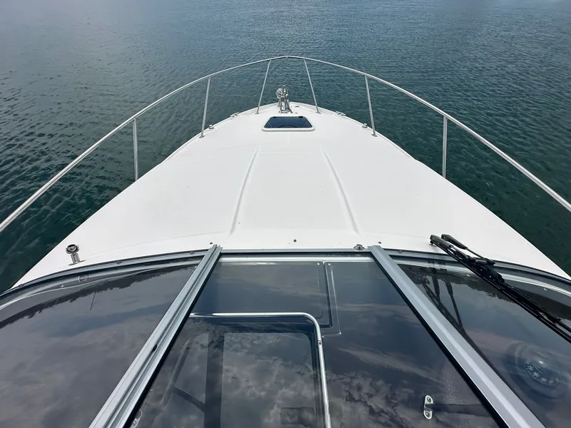 Slide: The Image of View from the bow of a 2014 Regal 30 Express on calm water, with clear windshield and railings. - 22